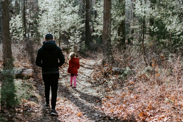 Photo by Kelly Sikkema man in black jacket and black pants standing in the middle of forest during daytime