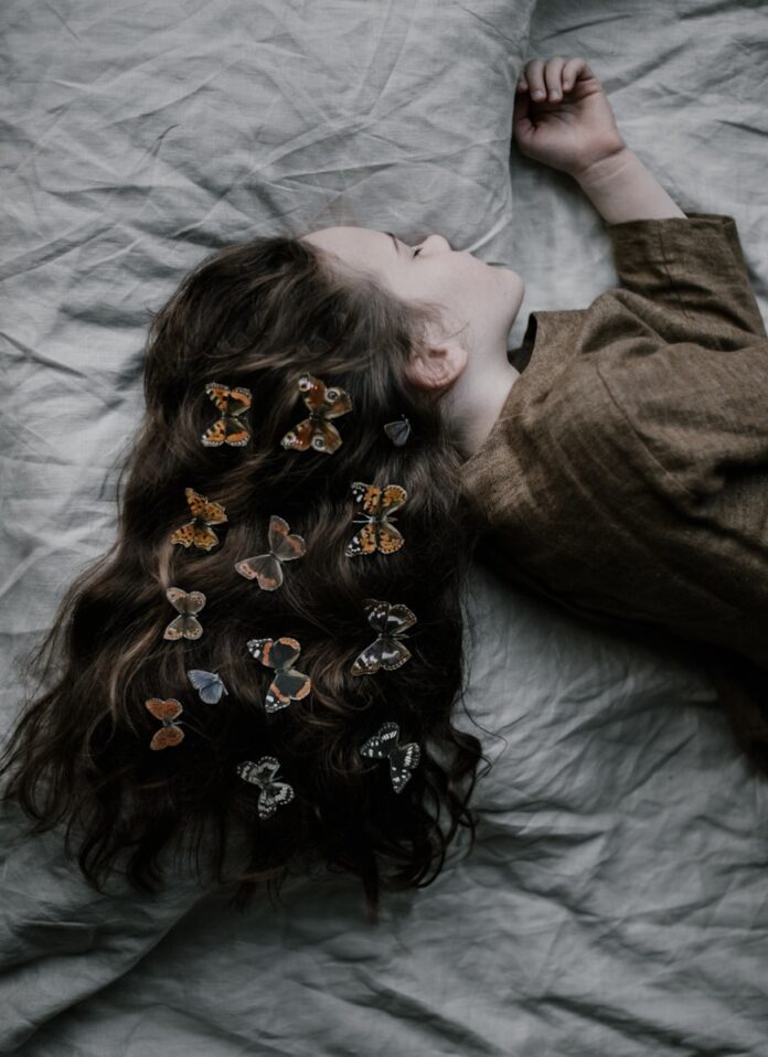 Photo by Annie Spratt girl lying on gray bed sheet