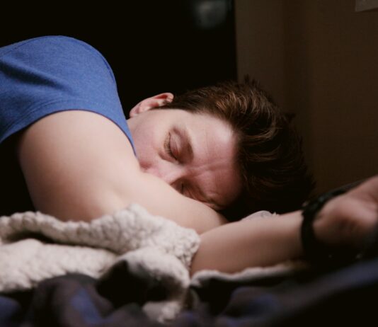 잠을 줄이는 방법 woman in blue shirt lying on bed