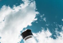 여름철 건강관리, 똑똑하게 준비하는 5가지 방법 a hand holding a water bottle in front of a blue sky