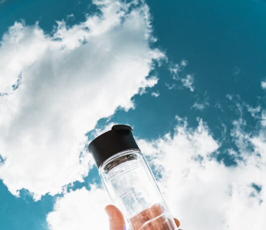 여름철 건강관리, 똑똑하게 준비하는 5가지 방법 a hand holding a water bottle in front of a blue sky