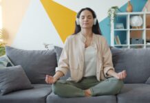 집에서 즐기는 ‘마음 챙김 스트레칭’, 일상에 활력을 더하다 Woman meditating on couch with headphones on