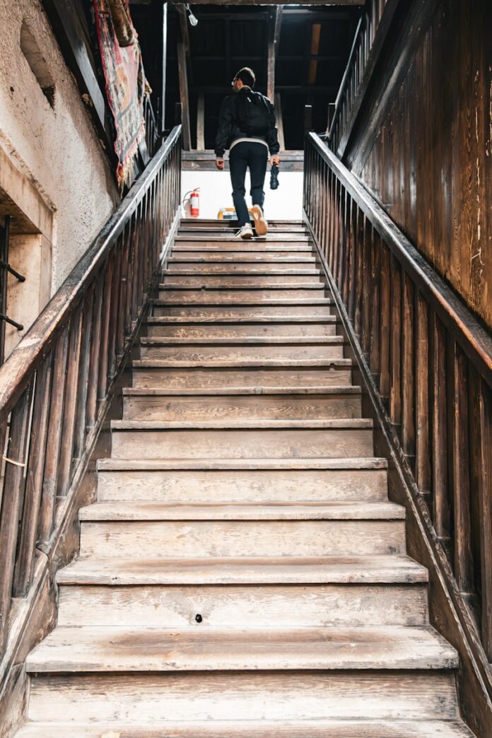 A person walks up a wooden staircase.